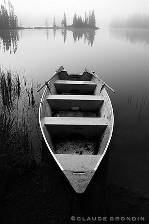 black and white image of a row boat on a foggy morning